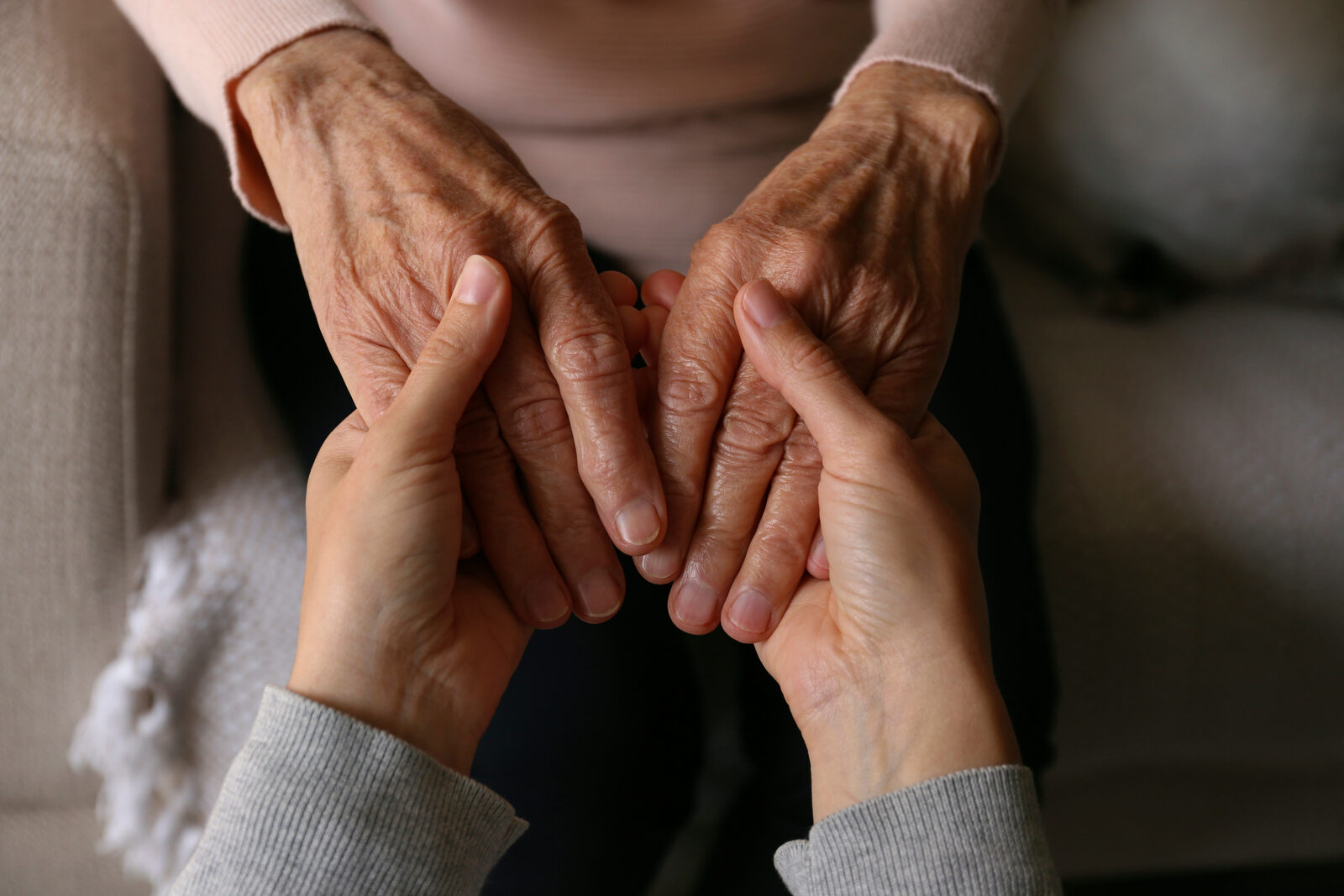 Younger hands holding the hands of an older loved one
